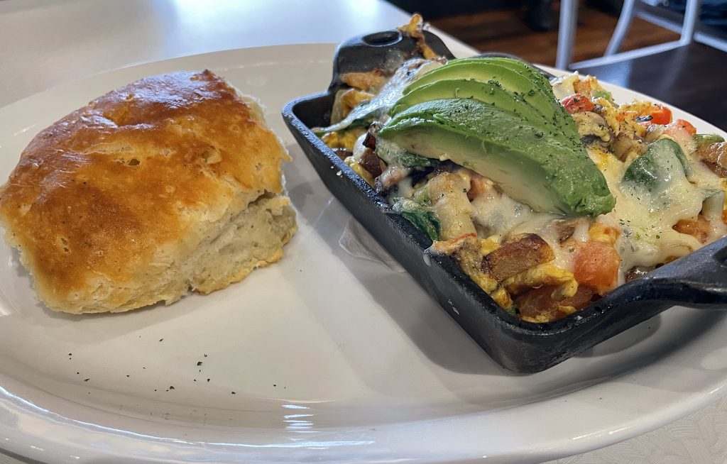 The Yard Work skillet dish offers scrambled eggs, cheese, and avocado atop a bed of sauteed veggies and herbs. It comes with your choice of bread or Big Bad Breakfast's fluffy black-pepper buttermilk biscuit.