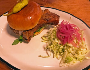 Portage House’s bone-in fried pork chop sandwich.