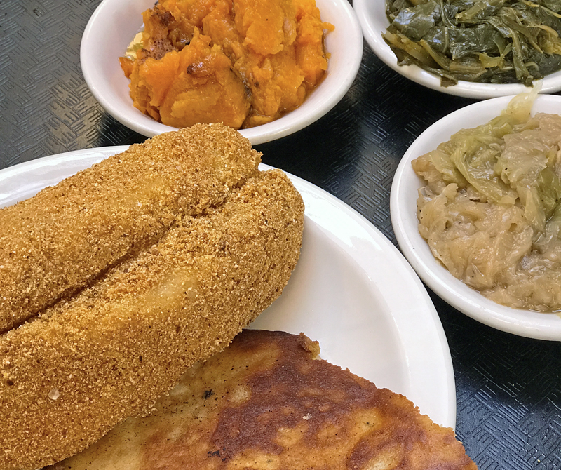 Fried catfish with sides of sweet potatoes, greens and cabbage at Irma Dee’s.