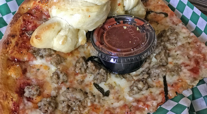 An oversize slice topped with house-made sausage and a couple of garlic knots at Butchertown Pizza Hall.