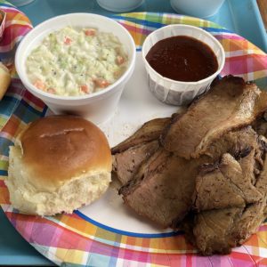 Holy Smokes’ thin-sliced, smoky brisket with creamy slaw, a dinner roll, and sweet-hot tomato-based sauce.
