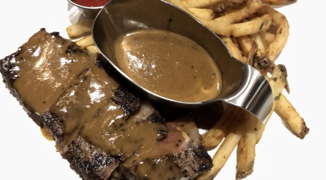 Steak & Bourbon’s steak and frites features New York strip steak au poivre.