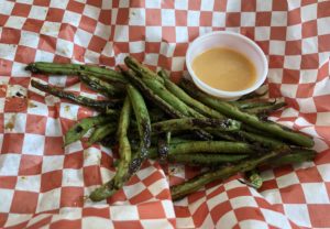 Cast-iron charred green beans are dusted with peppery spice and served with savory Japanese-American Yum Yum sauce at Six Forks. 