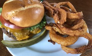 Shady Lane's Brownsboro burger, plated and ready to eat, with a side of onion rings.