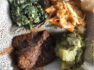 Queen of Sheba's meat and vegetable combination includes chicken doro wot, beef alicha sega wot, collards gomen wot and cabbage atakilt on a base of injera flatbread.