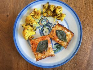 A couple of squares of vodka pizza and a serving of roasted turmeric cauliflower look right at home on an iconic Louisville Hadley Pottery plate.