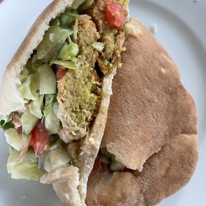 We've carved an Alwatan falafel in half to display its generous filling of tender falafel balls, lettuce, tomato, and creamy tzatziki sauce in a fresh, tender pita. 