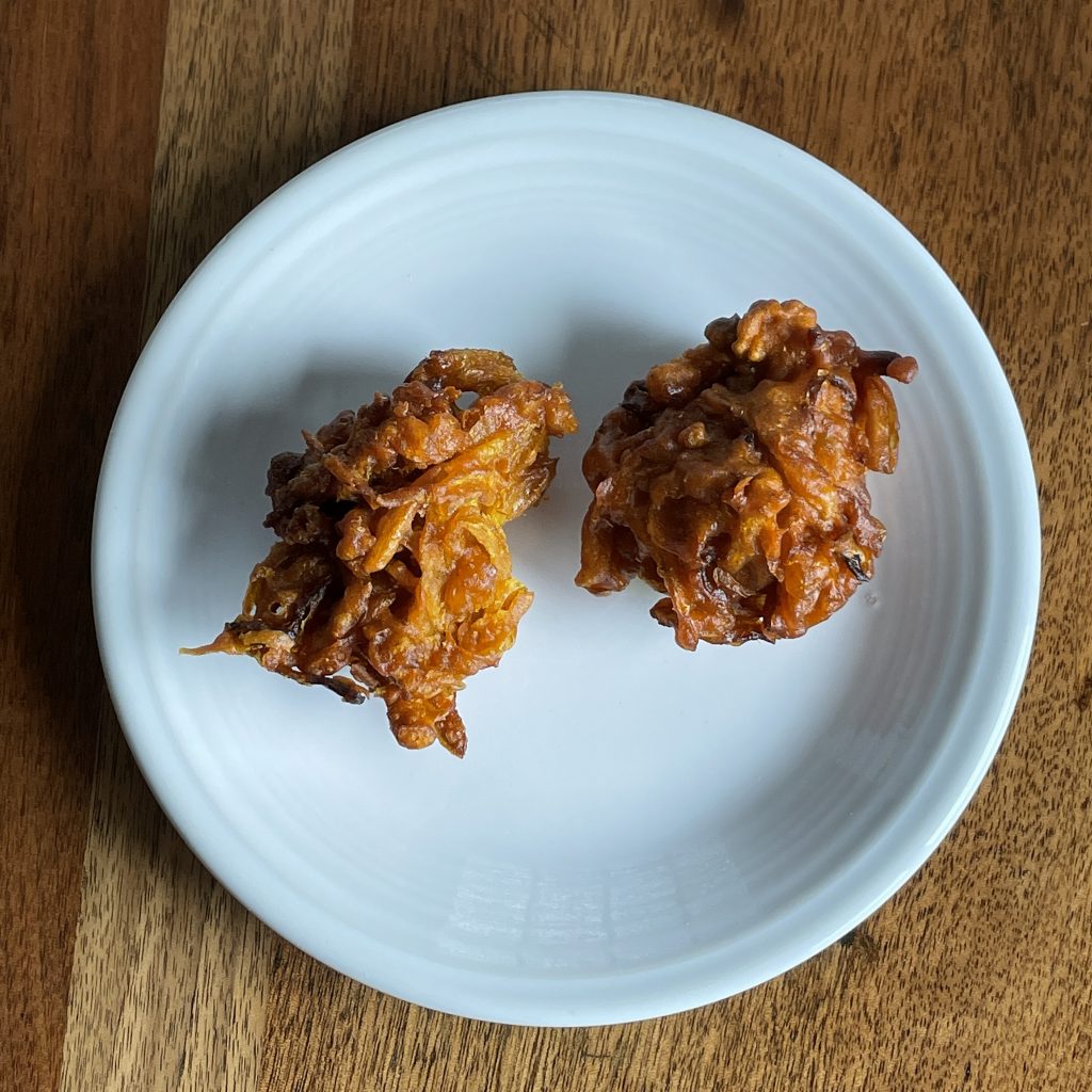 Tikka House's onion pakora appetizers are golf-ball size balls of onions and spice held together with chickpea-based gram flour batter and fried dark golden-brown.