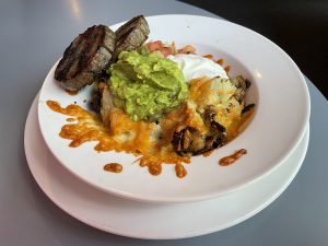 Home fries, two cheeses, guacamole and salsa make Le Suerte's potato melt a filling brunch plate, with a pair of breakfast sausages on the side.