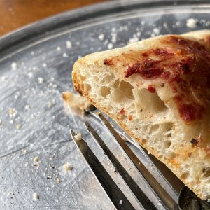 Large holes in the crust edges reveal quality breadmaking with wet dough, signaling serious attention to pizza details.