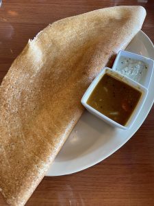 Masala dosa, an iconic South Indian brunch dish, wraps a huge rice-flour crepe around spiced potatoes with savory sambar soup and coconut chutney on the side.