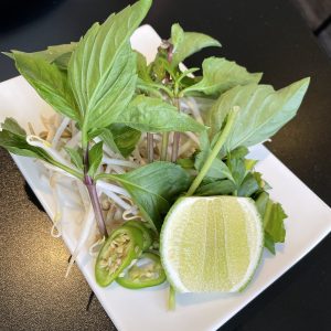 In traditional Vietnamese style, a pile of fresh greens, herbs, and hot peppers accompanies every bowl of pho.
