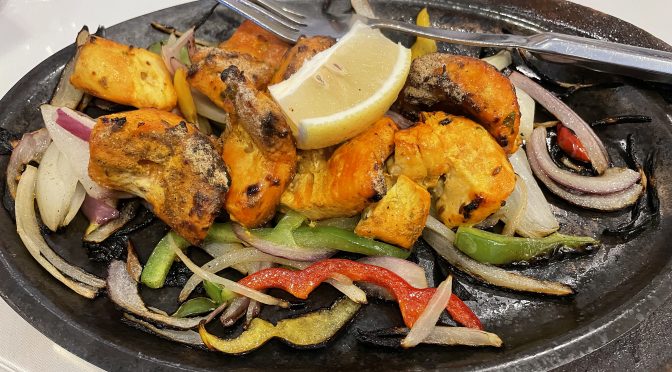 Straight from the scorching heat of the tandoor oven, skewered reddish-golden chunks of seasoned swordfish and crisp grilled veggies arrive sizzling like fajitas on a heated steel plate.