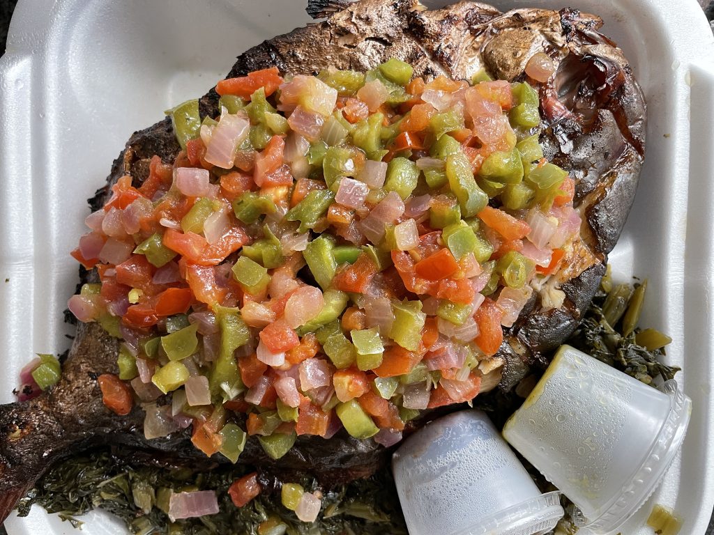 A whole pompano grilled over coals adds a smoky flavor. It's served on a bed of greens and topped with a pretty mix of neatly diced mixed veggies.