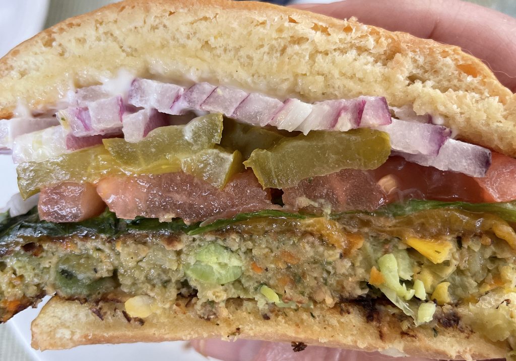 A peek inside the veggie burger reveals a meaty, textured chickpea patty popping with edamame and yellow corn. Dressed like a burger. Passes our taste test.