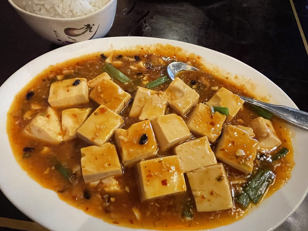 Mapo tofu, another Sichuan standard, is a simple but appealing preparation of silken tofu cubes bathed in a glossy, thick sauce with black beans and plenty of spicy red-chile flakes.