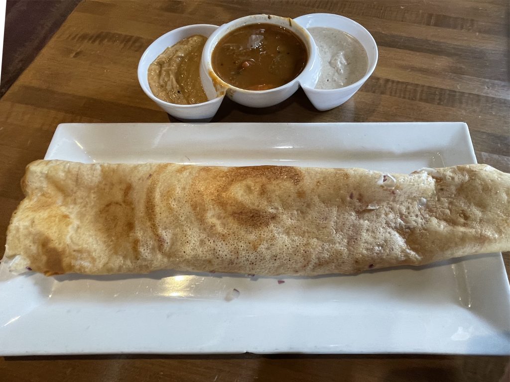 Substituted for a more traditional masala dosa, this huge rice- and lentil-flour crepe is filled with lightly sauteed, finely chopped red onions, with spicy sambar and chutneys on the side.