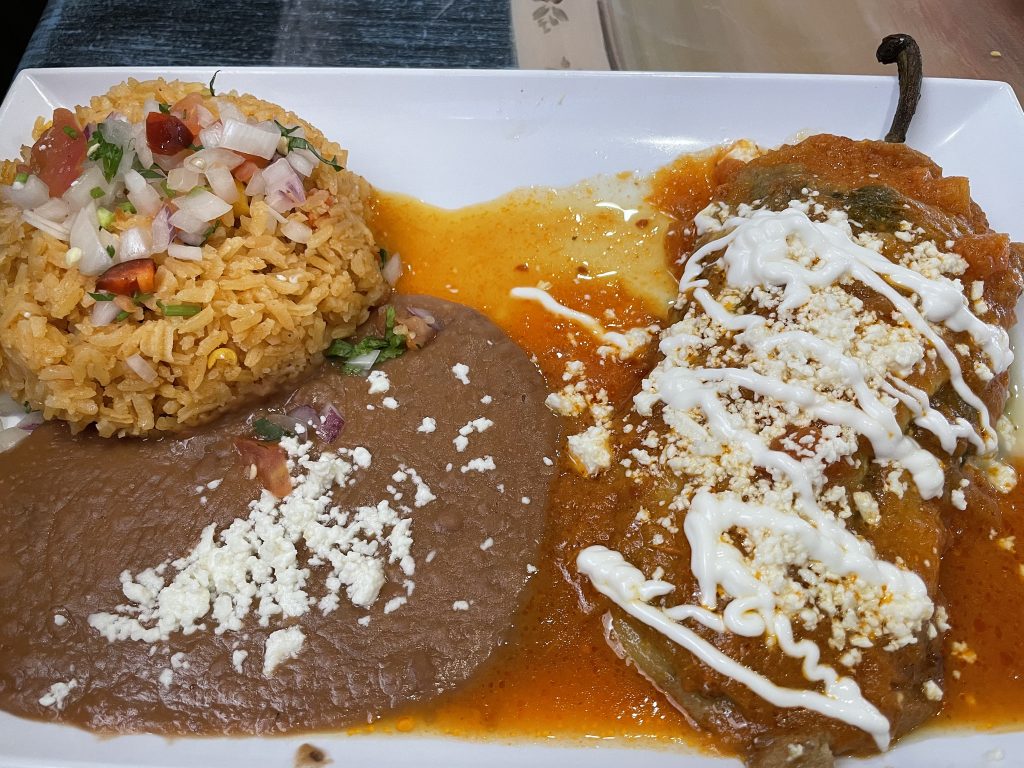 A chile relleno plate is built on a large, mild poblano chile stuffed with cheese or ground beef; it comes with Mexican-style rice and beans.