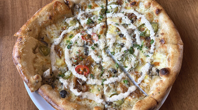 The yummy Mighty Mushroom pizza at Locals brings together a mighty mix of seasonal mushrooms, caramelized onion, house-pickled chili, cheese, aioli, and garlic and oil.